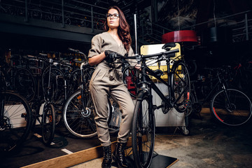 Fototapeta na wymiar Hardworking attractive woman is posing with bicycle at workshop.