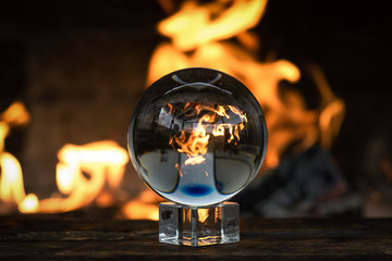 Crystal ball on a magic table on a burning fire flame background.