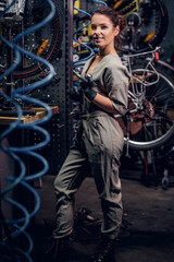 Diligent attractive woman is fixing bicycle at busy workshop in between pneumatic wires.