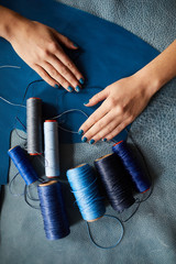 Above view closeup of female hands sewing leather clothes in dressmaking shop, copy space