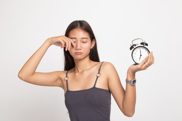 Sleepy young Asian woman with a clock in the morning.