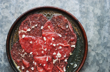 Delicious raw beef carpaccio with parmesan cheese in a plate top view space for text 