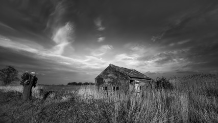 Alte Hütte vor dramatischem Wolkenhimmel - monochrom