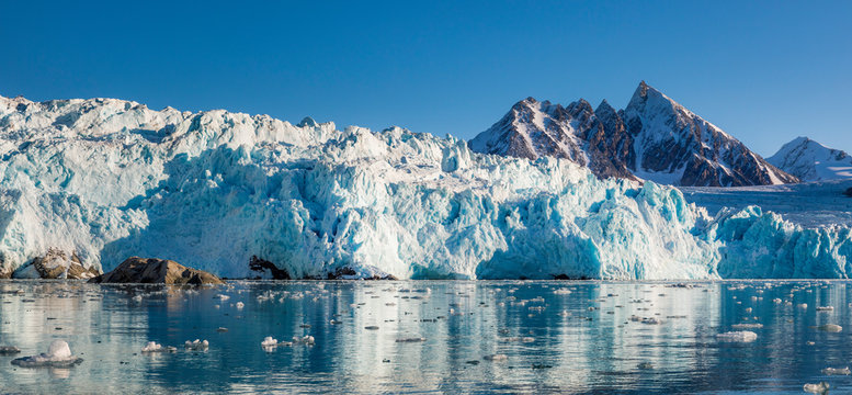 Glacier melting into water with mountains in distance