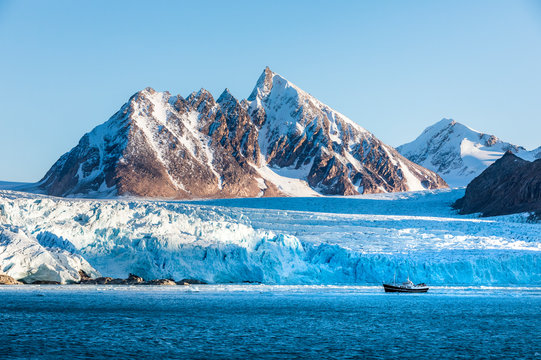 Boat sailing past sharp mountain peaks