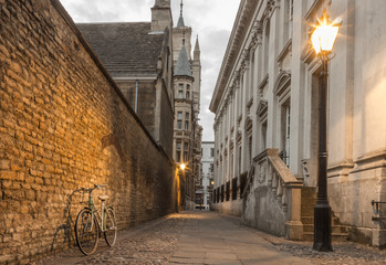 Narrow street at dusk in Cambridge UK, street lights & a bike