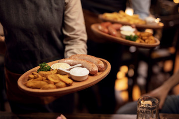 Unrecognizable waiter serving food to guest in a restaurant.