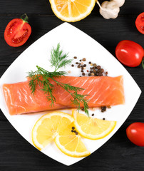 slice of red fish with lemon and fruit on a black background