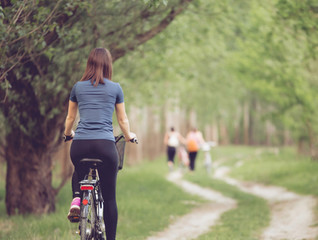 Woman biker cycling in park from behind