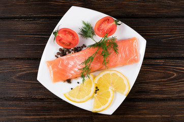 .red fish with lemon and tomatoes on a white plate