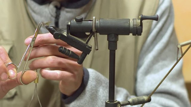 Man making trout flies. Fly tying equipment and material for fly fishing preparation .