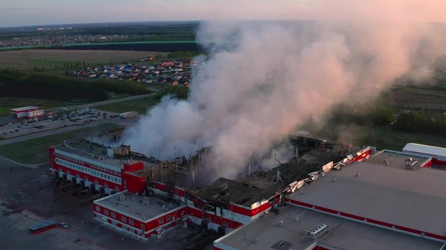 Heavy smoke in burning industrial warehouse or storehouse industrial hangar from burned roof, aerial view of fire disaster