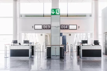 Fotobehang Front view of a bright interior of an airport terminal gate exit zone follows to an aircraft boarding area with ticket check desks in the foreground, computer monitors, information screens on the top © skyNext