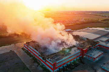Heavy smoke in burning industrial warehouse or storehouse industrial hangar from burned roof, aerial view of fire disaster