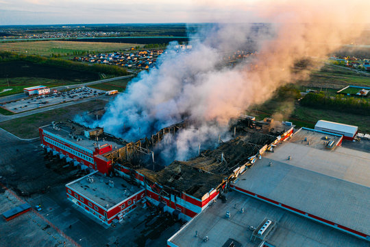 Heavy smoke in burning industrial warehouse or storehouse industrial hangar from burned roof, aerial view of fire disaster