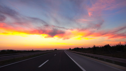 DRONE: Picturesque shot of a sunset shining on the highway crossing the country.