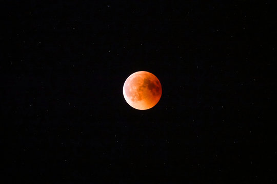 Detailed view of the glowing red moon's surface during a full lunar eclipse.