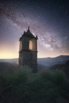 Old fortress building in rocky valley under bright night sky with majestic stars