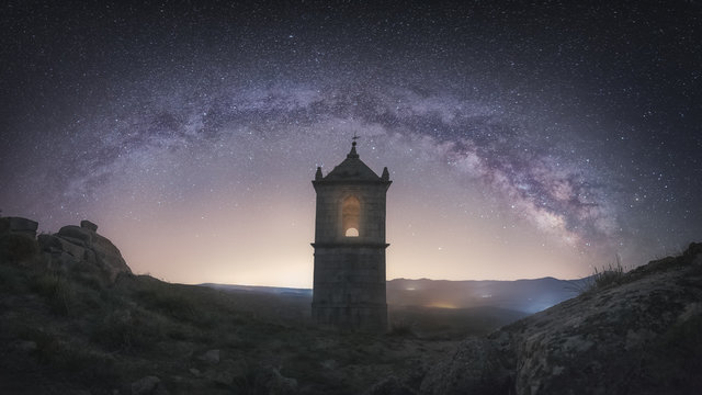 Old fortress building in rocky valley under bright night sky with majestic stars