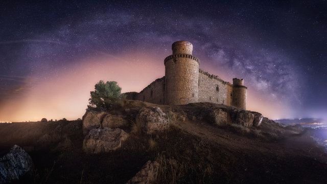 Mysterious ruined ancient fortress on night starry sky background