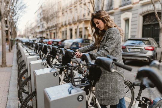 Lady choosing rental bicycle on parking lot