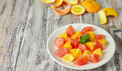 Fototapeta na wymiar Orange-grapefruit citrus salad on a shabby wooden table. copy space. summer vitamin salad.