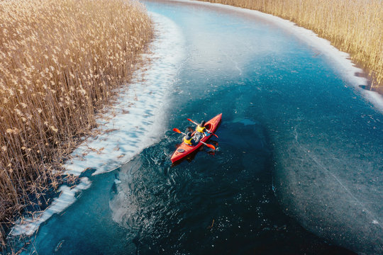 two athletic man floats on a red boat in river