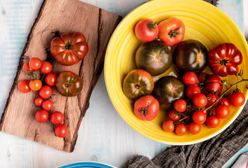 Cloth napkins placed on wooden table near ceramic bowls and lumber board with fresh red tomatoes