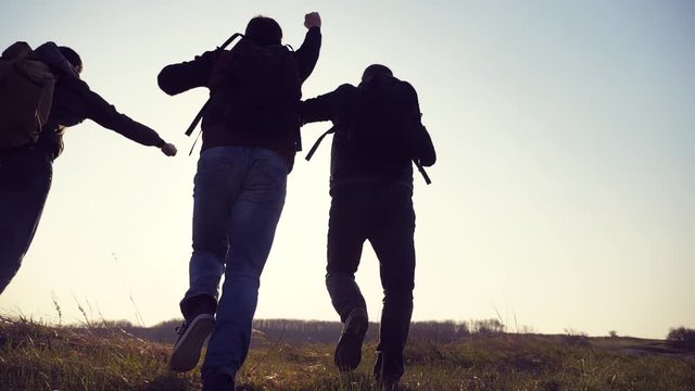 teamwork happiness business travel silhouette concept. group hikers of people happy run and jump slow motion video walking in lifestyle a field on trekking trip. tourists with backpacks traveling