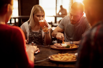 Group of friends having lunch and drinking beer in a tavern.
