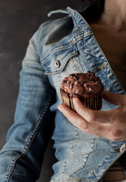 Unrecognizable female holding delicious chocolate banana muffin in hand near camera