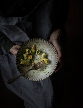 Anonymous woman holding a bowl of palatable pasta paccheri with fresh kale pesto and ground peanuts
