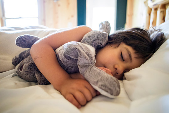 A toddler aged girl sleeping and taking a nap in a large bed.