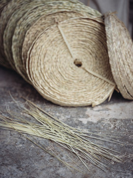 Set of rolls of woven dried palm fiber placed on floor in workshop