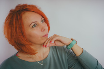 Young woman with red hair on white background. Portrait of a young attractive woman with a fashionable hairstyle.