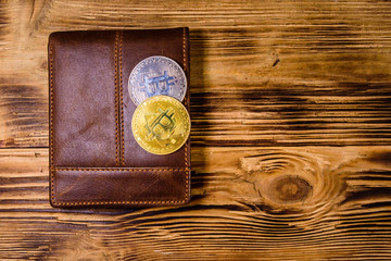 Brown leather wallet and bitcoins on the wooden background. Top view