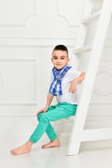 Fototapeta na wymiar Fashion beautiful little boy in bright pants and t-shirt and scarf