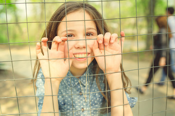 Beautiful girl, behind the fence locked in a cage.