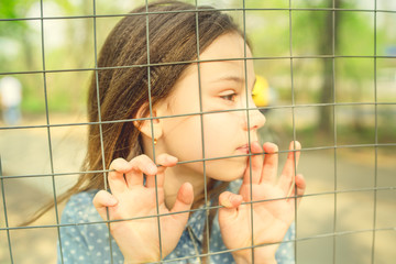Beautiful girl, behind the fence locked in a cage.