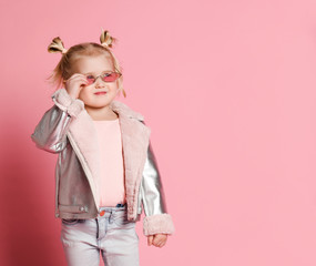 Portrait of a little girl in stylish clothing posing on pink background and playing up
