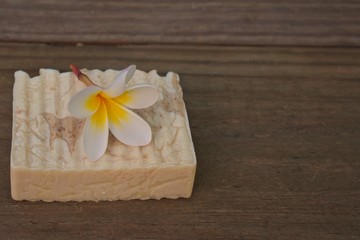 Handmade soap bar with plumeria on timber with copy space