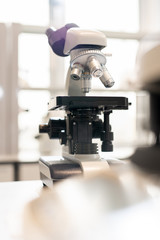 Close-up of modern microscope for biological researches places on table in laboratory, focus on objective lens and cross table