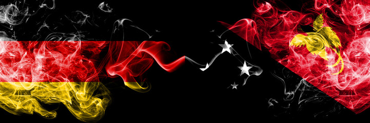 Germany vs Papua New Guinea smoky mystic flags placed side by side. Thick colored silky smoke flags of Deutschland and Papua New Guinea