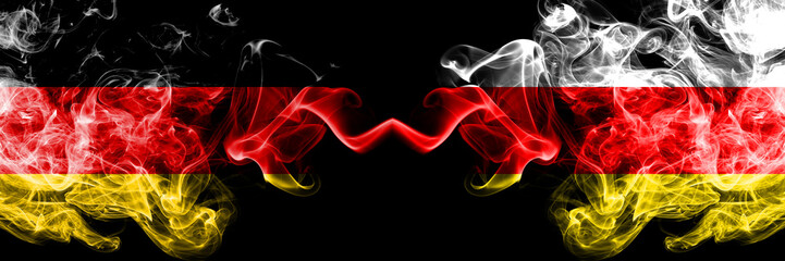 Germany vs South Ossetia smoky mystic flags placed side by side. Thick colored silky smoke flags of Deutschland and South Ossetia