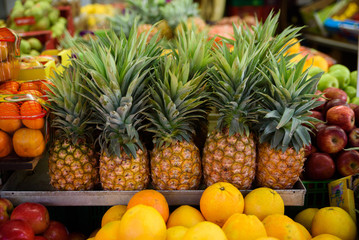 Lot of fresh ripe pineapples lying on each other on outdoors market.