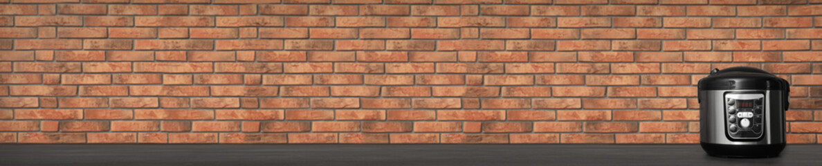 Modern multi cooker and products on table against grey background. Space for text