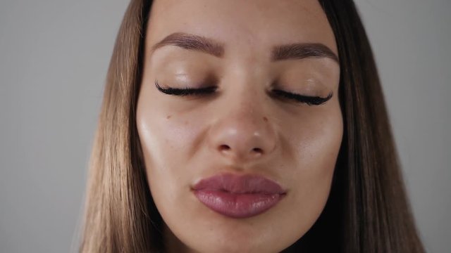 Beautiful Fashion Luxury Makeup, hyaluronic acid long eyelashes, perfect skin facial make-up. Beauty Brunette model woman holiday make up close up. Eyelash extensions, big lips false eyelashes smiling