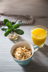 Bowl of homemade oatmeal porridge with almonds and orange juice