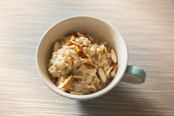 Bowl of homemade oatmeal porridge with almonds and orange juice