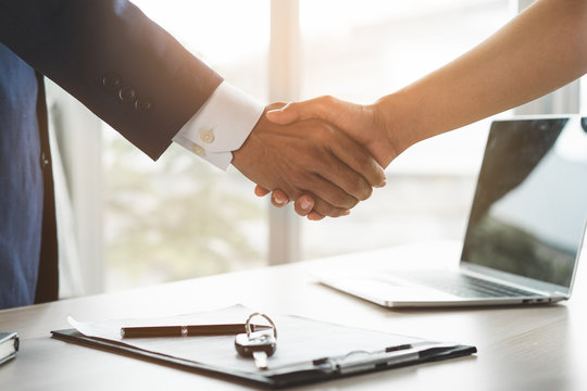 Car rental service concept. Close up view Hand of agent giving car key to customer after signed rental contract form.